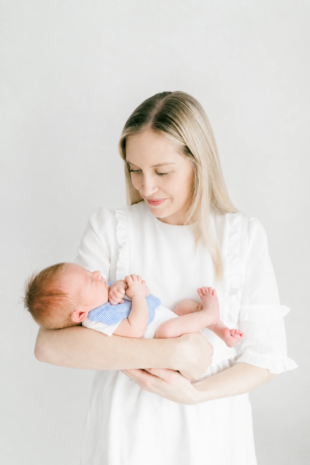 Mother holding her baby wearing the Oliver striped scalloped bib