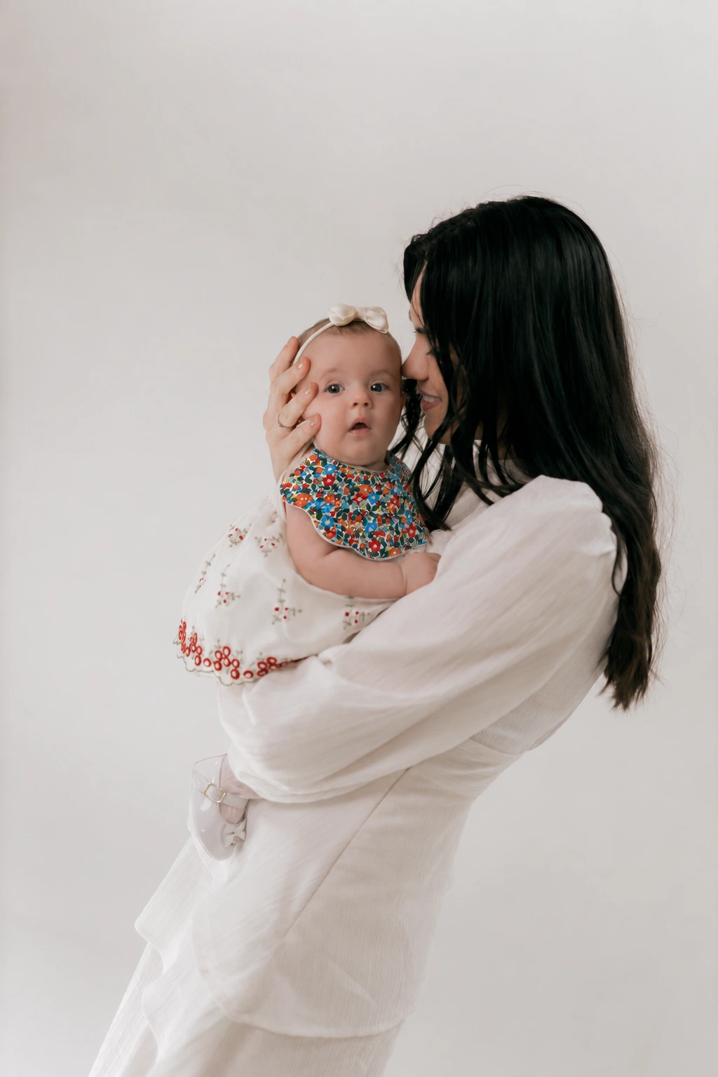 Mother holding her baby wearing the Ruby scalloped floral bib